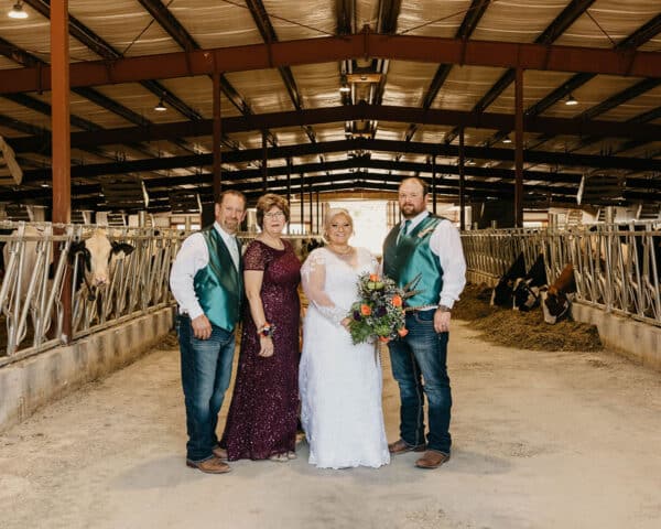 Virgil, Dawn, Karsen and Kody Haag family photo at Dan and Karsen Bentley's wedding at Virhada Holsteins in Mt. Horeb, WI. COw barn wedding photo.