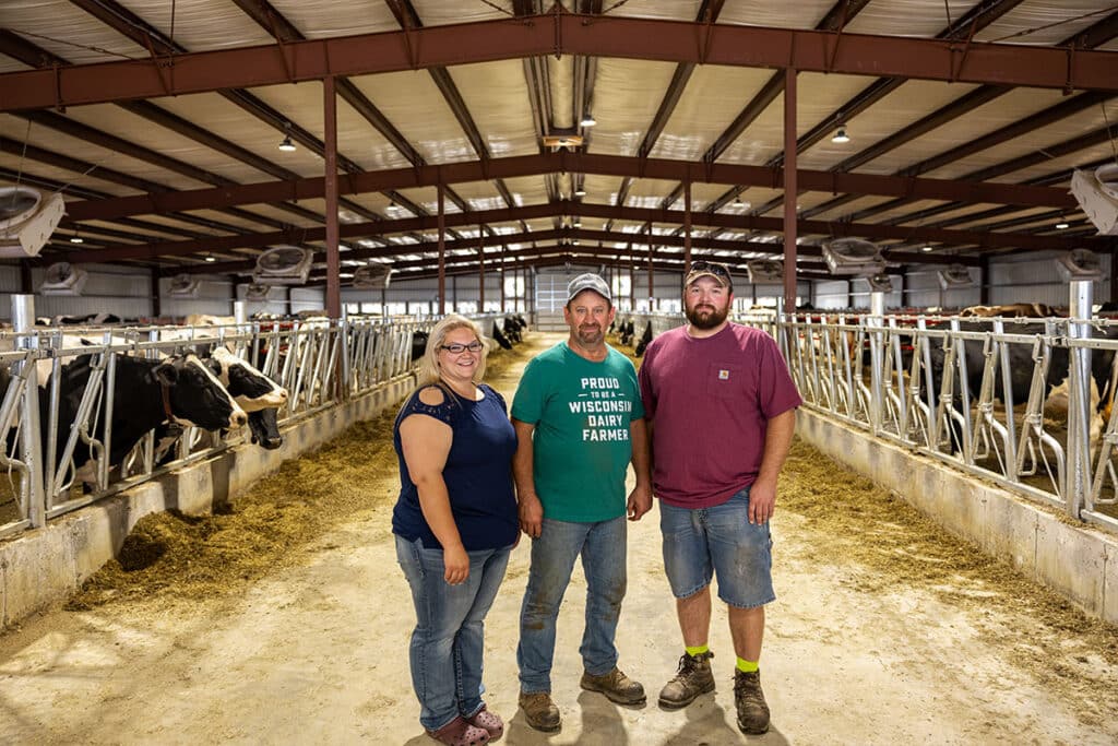 Virgil, Karsen, and Kody Haag family dairy farmers in cow barn.